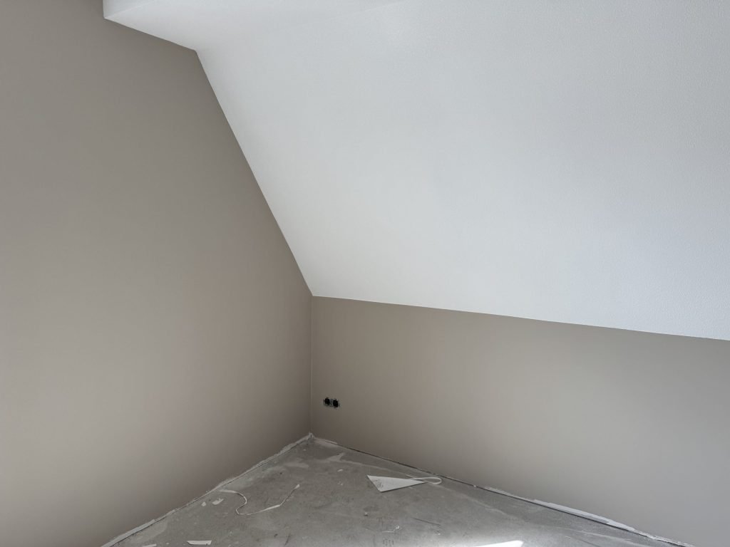 Zolderkamer met een schuine wand in wit en rechte wanden in een zachte beigetint